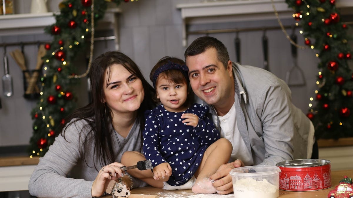 Happy family baking Christmas cookies together in a decorated kitchen.